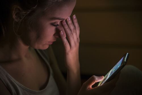 Girl upset looking at phone symbolizing nonconsensual porn